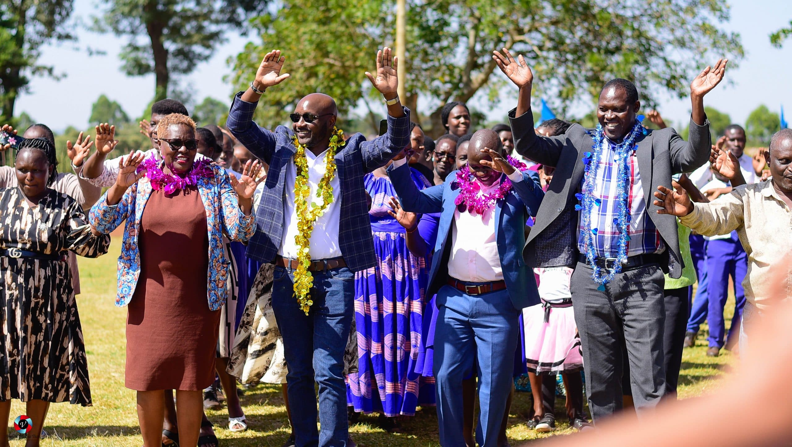 Peter Rotich and community members raising their hands together at a Rotich Foundation school event