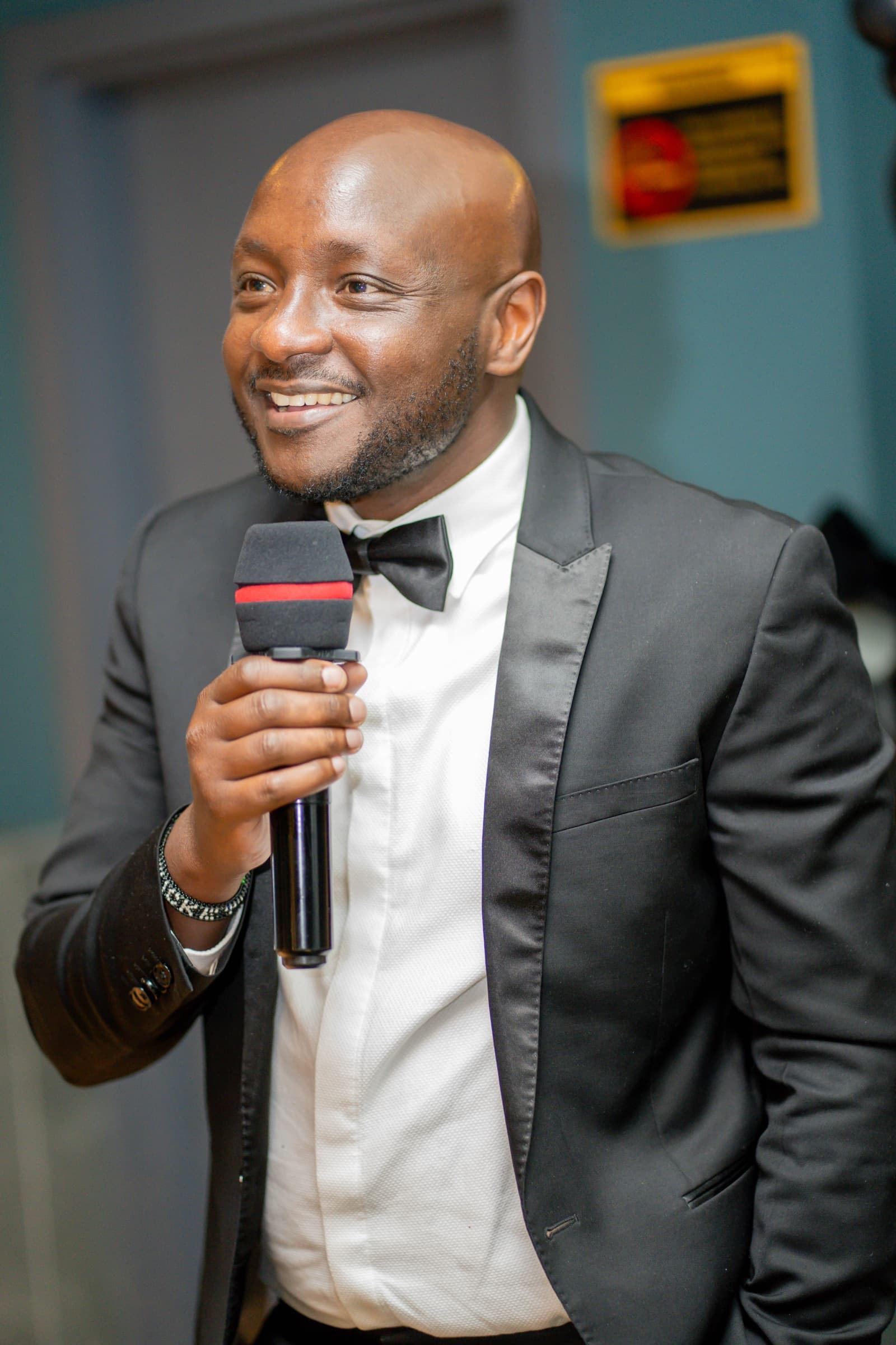Peter Rotich speaking into a microphone in a tuxedo